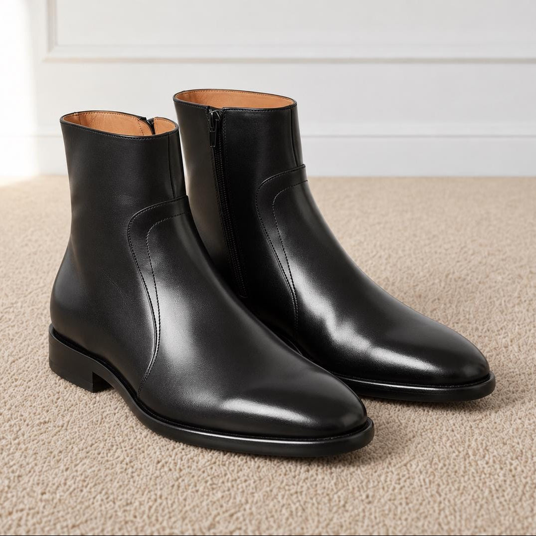 Pair of black polished leather side-zip boots with a plain toe and tan lining on a neutral carpet